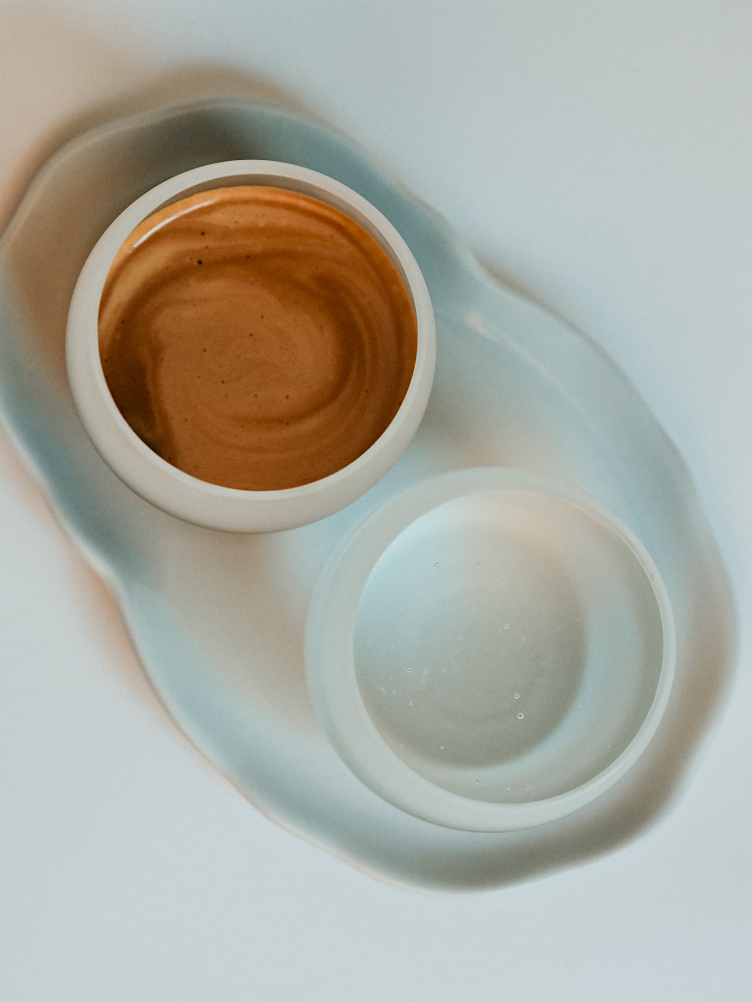 Espresso and water served in ceramic cups on a tray